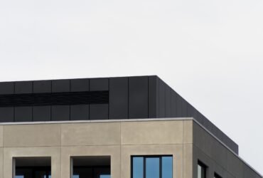 A low angle shot of a concrete building with mirror windows under the clear sky - great for a cool wallpaper
