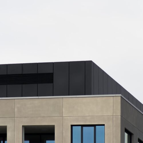 A low angle shot of a concrete building with mirror windows under the clear sky - great for a cool wallpaper